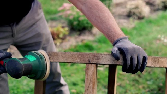 Mand grinding old table in the garden,  focus on hands 120fps