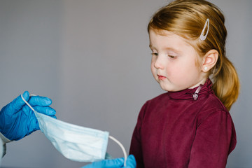 Coronavirus. Nurse, doctor in a protective suit, puts medical mask on face for child. Preventive measures against Covid-19 infection. Concept of protection against influenza, corona virus epidemic.