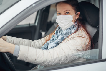 a woman driving a car puts on a medical mask during an epidemic, a taxi driver a woman in a mask,...