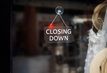 Closing Down  sign painted on the window of a dress shop.
