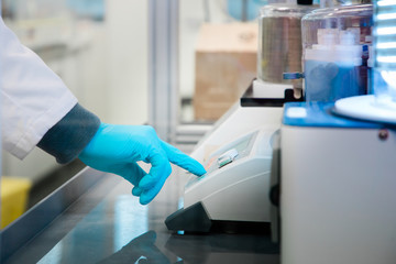 Closeup of man's hand pressing a button to perform analysis of sample suspected for coronavirus...