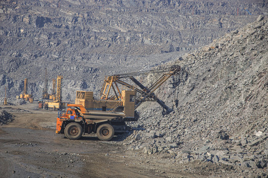 Excavator loads iron ore into a large dump truck