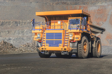 A large truck loaded with iron ore rides in a quarry