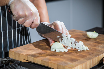 Chef cutting the onions on a board