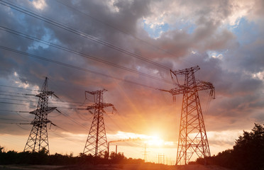 A silhouette of high voltage power lines against a colorful sky at sunrise.