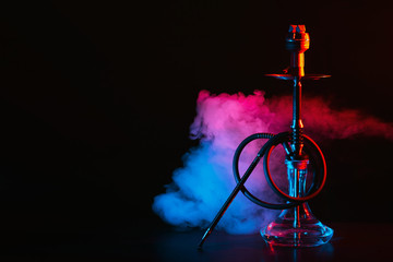 hookah with a glass flask and a metal bowl shisha with colored smoke on the table - obrazy, fototapety, plakaty