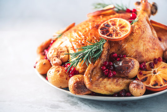 Whole roasted chicken with oranges, cranberries, spices and herbs. Copy space. Friends or family dinner. Festive Christmas table. Traditional Thanksgiving or Friendsgiving holiday celebration dish.
