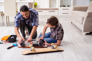 Young father repairing skateboard with his son at home
