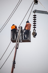 The electrician working or fixing the voltage pillars ot poles with crane in the sunnyday. 