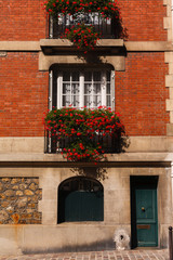 Fototapeta na wymiar facade of a brick house. Balconies with flowers. Paris, France.