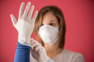 nurse with molded mask puts on surgical gloves to prevent coronavirus infections and prevent the spread of the world pandemic