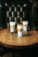 Three types of latte drink in cafe. Classic, caramel and mint latte. Vertical photo.