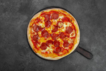 Pepperoni pizza with cherry tomatoes, cheese on black background