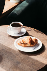 Fresh croissant with chocolate filling. Americano cup. Breakfast at the cafe.
