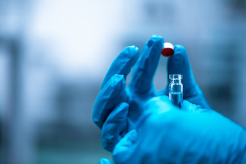Close up of hand pharmacist with test tube with vaccine against virus, pharmacy concept
