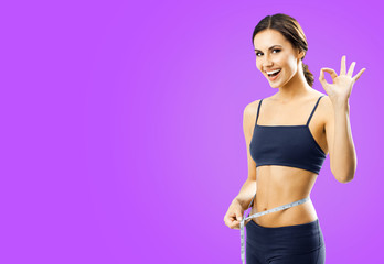 Cheerful woman in fitness wear with tape, showing okay gesture, over violet purple background.