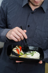 Man eating creamy risotto with microgreen and baked mackerel. Healthy food and diet concept, restaurant dish delivery. Take away of fitness meal. Weight loss nutrition in boxes.