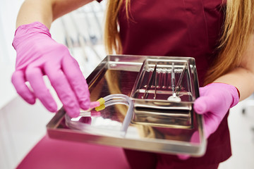 Close up view of female dentist in uniform that standing in stomatology office with tools in hands