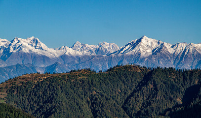 snow covered mountain ranges with forests in foreground, trees, valleys