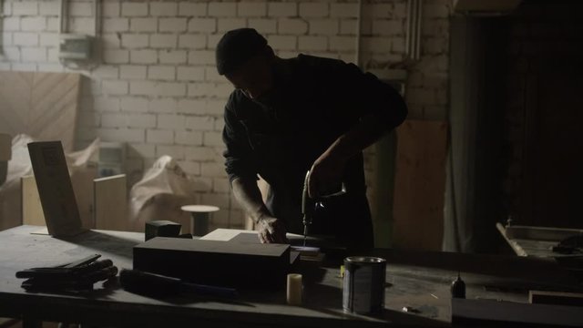Mann bohrt in ein brett 