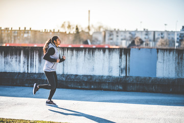 Fototapeta na wymiar Young woman jogging in an urban environment