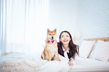 Pet Lover concept. An Asian girl is learning and parody the smile of her Shiba Inu dog. A girl is laying with a Shiba Inu dog on a bed.