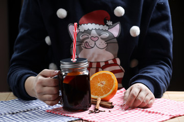 woman in a christmas pullover holding glass of mulled wine 