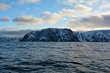 Fototapeta na wymiar Nordkapp with snowy cliffs and blue water of Barents Sea