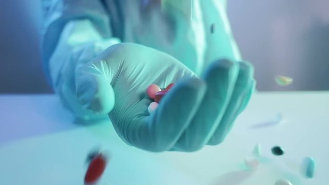 COVID-19 outbreak. Drug manufacturing. Pills scattering into nurse hand in protective glove.