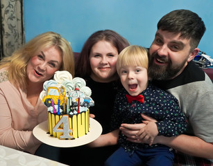 The family celebrates the birthday of a four year old son. Family with a cake and the number four. Birthday of the son. Dad and mom with children and a cake.