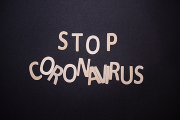 stop coronavirus written on black background with wooden letters