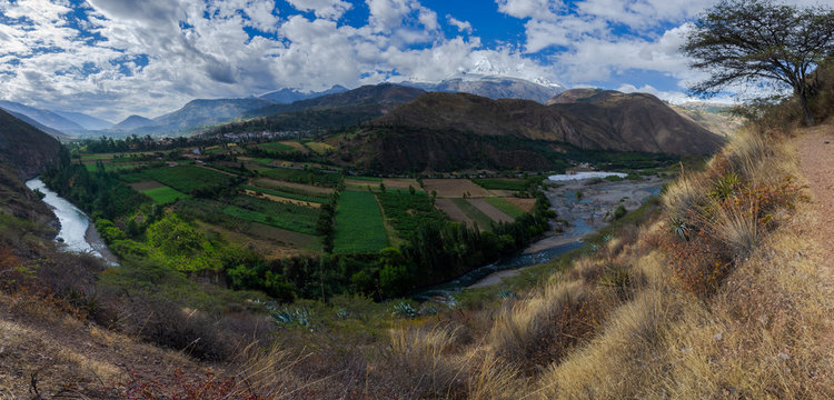 Panoramic daytime landscape with clouds of the callejon de huaylas with rio santa, mountains of the andes, agricultural fields and path to trek in peru