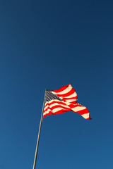 American flag waving in the wind with blue sky background