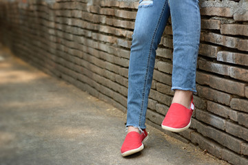 Young girl wearing ripped jeans and red shoes