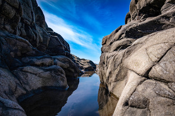 rock in sea,  puddle of water between rocks.