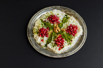 Traditional Ramadan Dessert is Gullac ready to eat on vintage metal tray on black surface.