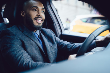 Happy adult ethnic executive man dreaming while driving car standing in traffic jam