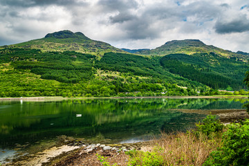 Green hills of Arrochar Alps reflecting in Loch Long. Beautiful Scottish Highlands summer scenery.