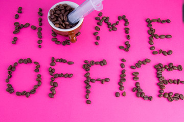 Home office made of coffee beans laid on a pink background