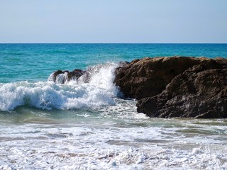 Nature photo of rocks with waves in blue ocean