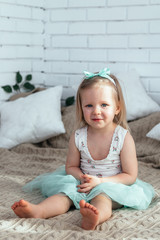 A little girl is sitting on the bed.