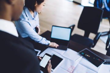 Multiracial coworkers sharing business ideas by using smartphone and laptop