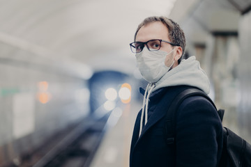 Coronavirus crisis. Male follows quarantine rules wears protective medical mask, travels in public transport cares about health during epidemic or pandemic. Danger of catching virus in city transport