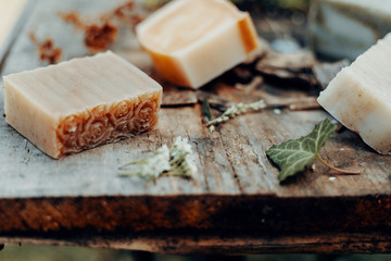 Various handmade natural soaps on a vintage wooden table with decoration