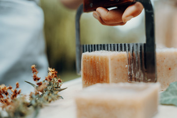 Woman is making handmade natural soaps on an old wooden table
