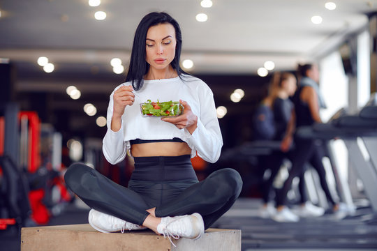 Beautiful sport woman in sportswear eating salad in gym.