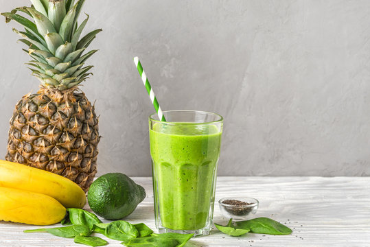 Glass with green healthy smoothie detox made of spinach, pineapple, avocado, banana and chia seeds