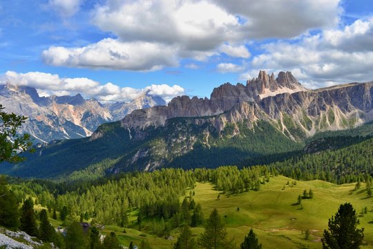 Dolomites mountains, Italy. Sunny day, blue sky, white clouds, green grass. 
