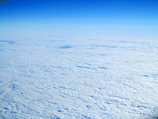 view from the wing of the plane to the ground and to the blue cloudy sky