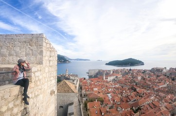 Tourist woman enjoying view from the top of the fortress old city wall of Dubrovnik, Croatia